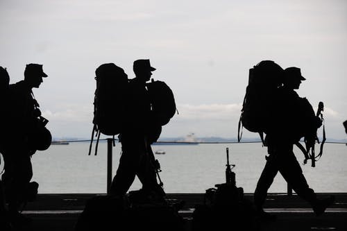silhouette of military soldiers walking from left to right